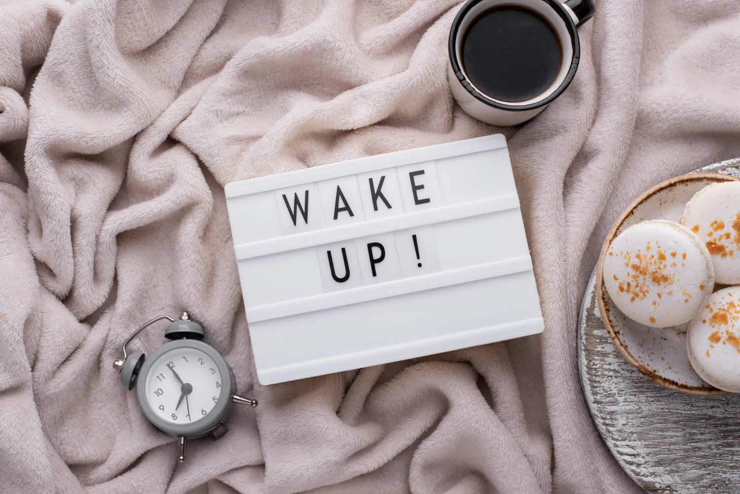 Alarm clock and coffee cup with 'Wake Up' written, representing how to build a morning routine that sets you up for success.