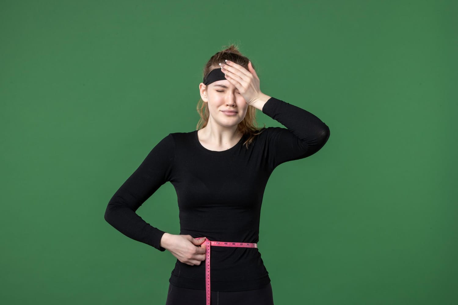 Woman measuring her waist with a tape, losing weight continuously.