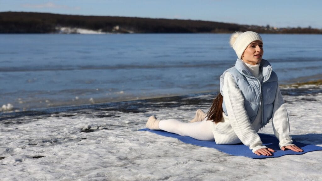 Cold Yoga: A Mindful Chill for Body, Breath & Balance 6 Girl practicing cold yoga on a snow-covered field at sunrise, embracing the chill with graceful posture