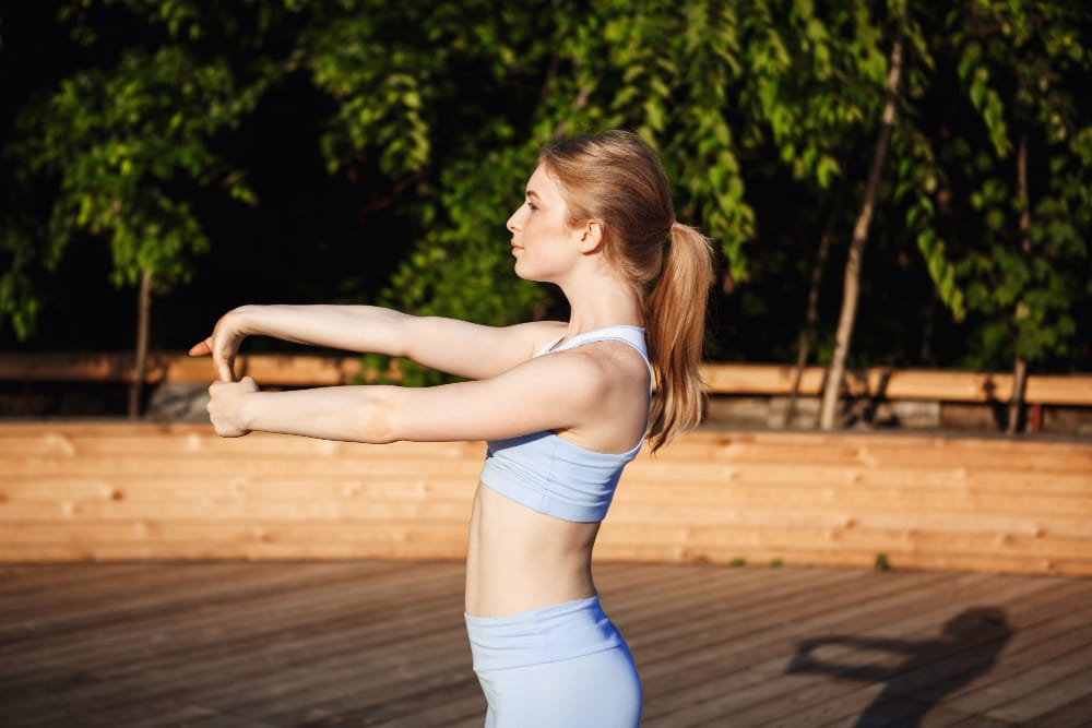 Woman standing straight and stretching outdoors, demonstrating how to improve posture with simple daily exercises.