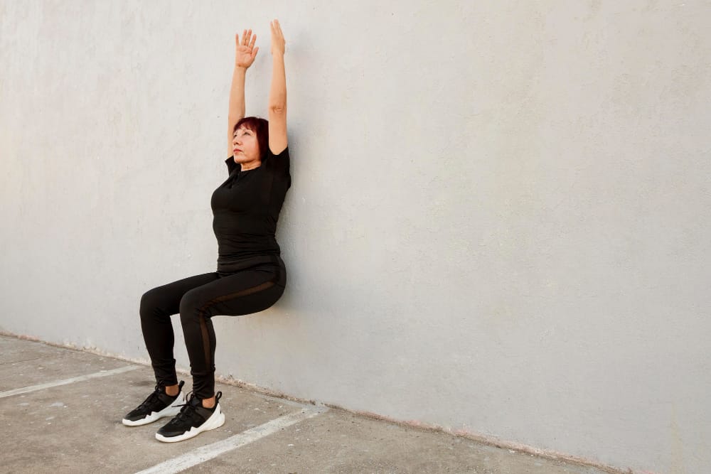 How to Improve Posture With These 3 Simple Exercises 2 woman performing wall angels exercise to show how to improve posture by aligning spine and shoulders.